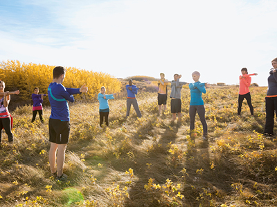 Sportgruppe beim Dehnen im Sonnenuntergang